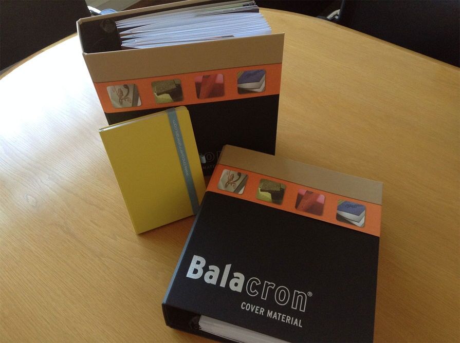 Dossiers de amostras de materiais de capa BN International e Balacron sobre uma mesa